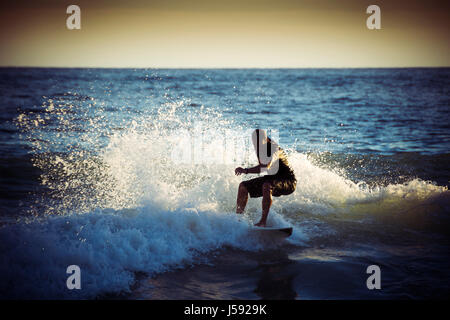 Surfer la vague silhouette d'équitation en début de soirée la lumière Banque D'Images