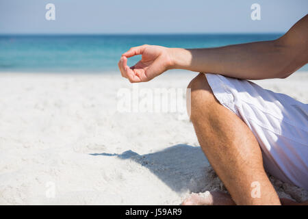 La section basse de l'homme à méditer sur la plage sunny day Banque D'Images