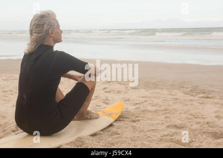 Vue arrière du senior woman sitting on surfboard Banque D'Images