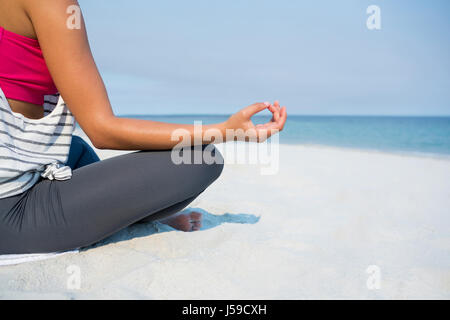 La section basse de jeune femme méditant à la sky au cours de journée ensoleillée Banque D'Images