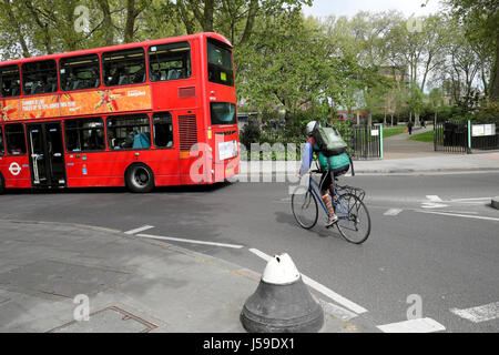 Cycliste homme équitation sa moto, portant sac à dos et petit vélo derrière un bus à impériale près du parc Newington Green London N5 UK KATHY DEWITT Banque D'Images