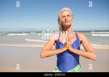 Close up of senior woman with hands clasped standing against clear sky at beach Banque D'Images