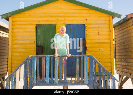 Portrait of senior man standing at beach hut sur sunny day Banque D'Images