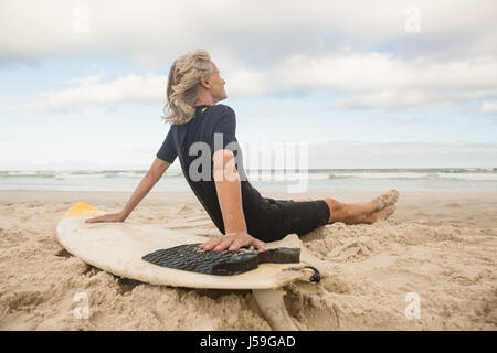 Vue latérale du senior woman leaning on surfboard Banque D'Images