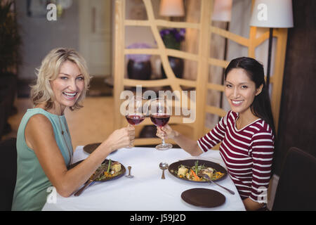 Deux femmes toasting glasses of red wine in restaurant Banque D'Images