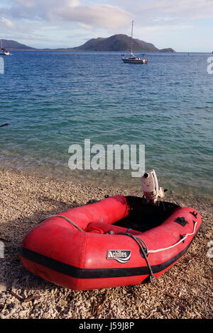 Petit bateau gonflable rouge sur la plage de débris de corail avec des yachts amarrés en arrière-plan, Fitzroy Island, Grande Barrière de Corail, Queensland, Australie. Pas de PR Banque D'Images
