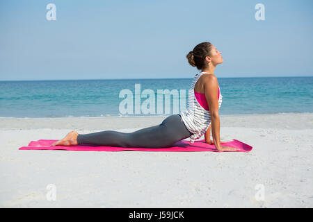 Toute la longueur de woman practicing cobra à poser sur la plage sunny day Banque D'Images