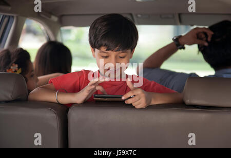 Portrait of happy boy using digital tablet in back seat of car Banque D'Images