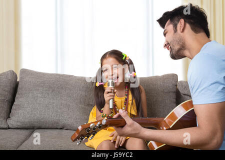 Père qui joue de la guitare et chant fille Banque D'Images