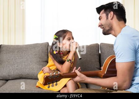 Père qui joue de la guitare et chant fille Banque D'Images