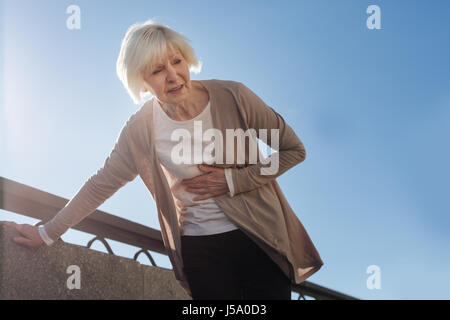 Vieille Femme se sentir à l'estomac à l'extérieur Banque D'Images