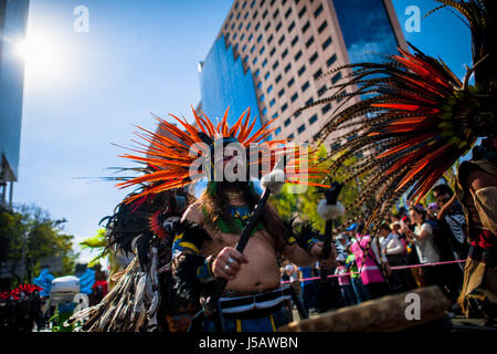 Un homme, portant un couvre-chef en plumes colorés inspirés par les Aztèques, tambour joue pendant le jour de la fête des morts à Mexico, au Mexique. Banque D'Images