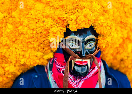 Un homme, vêtu d'un masque en bois noir avec des fleurs de souci, prend part à la Journée de la mort de festivités dans la ville de Mexico, Mexique. Banque D'Images