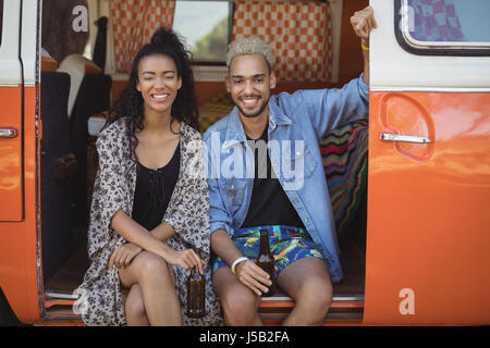 Portrait of happy friends holding beer bottles while sitting in van Banque D'Images