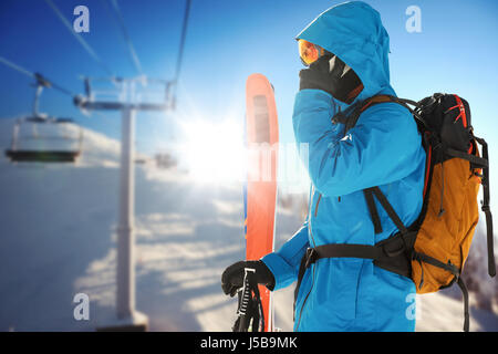 Tout en parlant au téléphone skieur holding skis contre téléski de la station de ski Banque D'Images