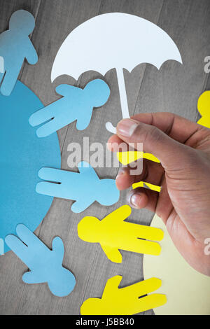 Main tenant un parapluie en papier contre papier jaune et bleu découper des chiffres sur la table en bois Banque D'Images