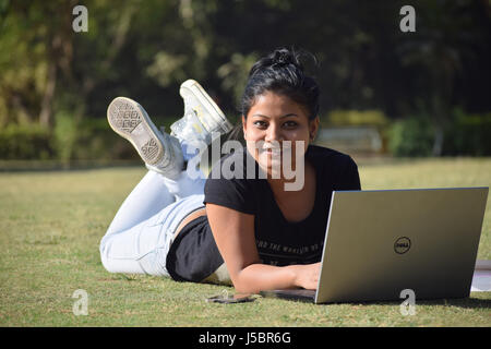 Jeune étudiante lying on grass with laptop and books, Pune, Maharashtra Banque D'Images