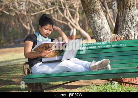 Jeune étudiante étudier sur banc avec coffre et books, Pune, Maharashtra Banque D'Images