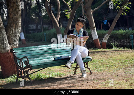 Jeune étudiante étudier sur banc avec coffre et books, Pune, Maharashtra Banque D'Images