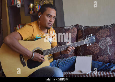 Portrait de beau jeune homme écoute de la musique et jouer de la guitare, Pune, Maharashtra Banque D'Images
