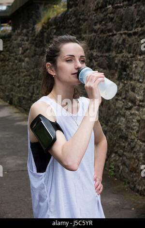 Femme athlétique de l'eau potable, alors que la formation à l'extérieur dans un cadre naturel. Concept d'action et d'un style de vie sain. Banque D'Images