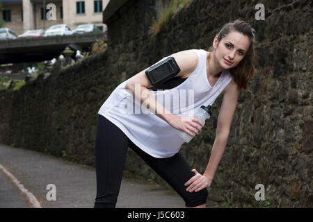 Femme athlétique de l'eau potable, alors que la formation à l'extérieur dans un cadre naturel. Concept d'action et d'un style de vie sain. Banque D'Images