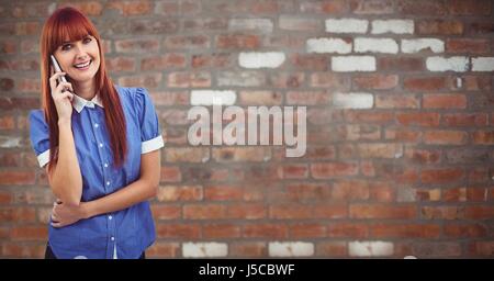 Digital composite of Smiling woman using smart phone against brick wall Banque D'Images