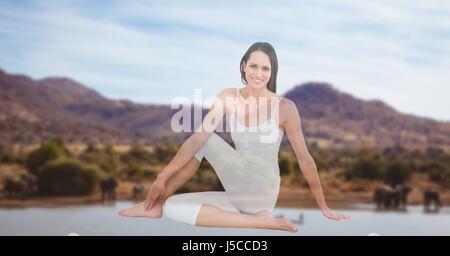 Digital composite of young woman performing yoga avec montagnes en arrière-plan Banque D'Images