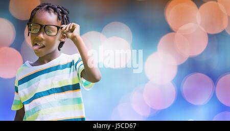 Digital composite of Playful boy sticking out tongue en maintenant les lunettes sur bokeh Banque D'Images