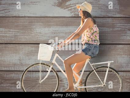 Digital composite de vue latérale du cycle de la femme contre le mur en bois Banque D'Images