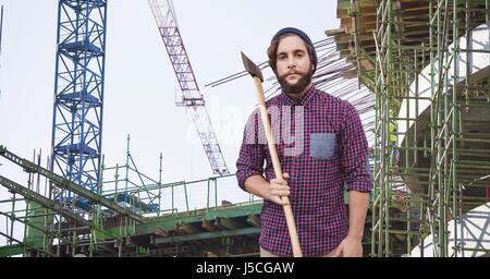 Digital composite de Hipster holding ax at construction site Banque D'Images