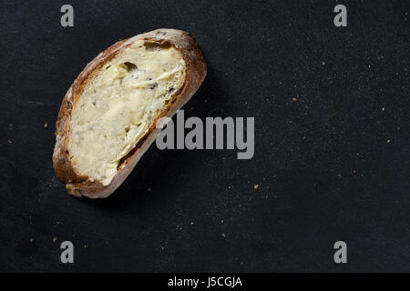 Une tranche de pain sur une plaque en ardoise noire. Banque D'Images