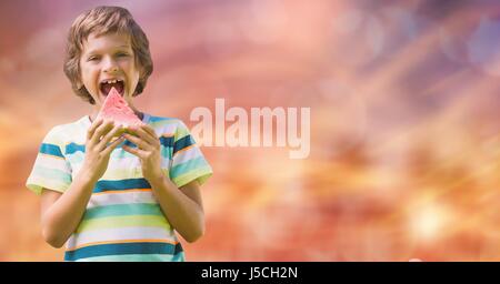 Digital composite de Happy boy having watermelon sur arrière-plan flou Banque D'Images