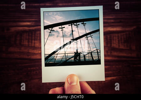 Main tenant polaroid carte postale de deux personnes silhouettes marcher sur Frankston Bridge au coucher du soleil. Des souvenirs de voyage gabarit de scrapbooking with copy space Banque D'Images