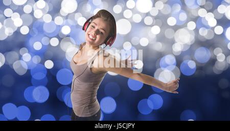 Digital composite of Happy woman dancing tout en écoutant de la musique sur le casque contre l'effet bokeh Banque D'Images