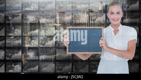 Digital composite of Smiling businesswoman holding blank slate écrans contre Banque D'Images