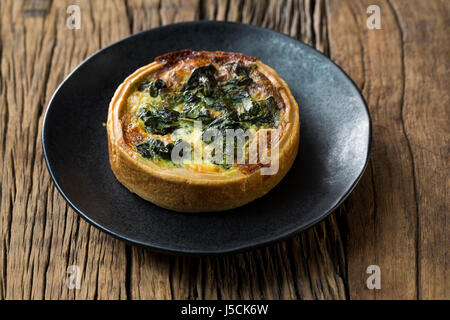 Quiche aux épinards faites maison. La nourriture est assis sur un fond de bois rustique. Banque D'Images