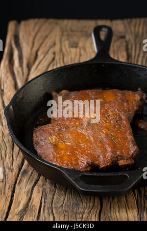 Côtes de porc grillées sauce barbecue en assis sur une table en bois rustique. Banque D'Images