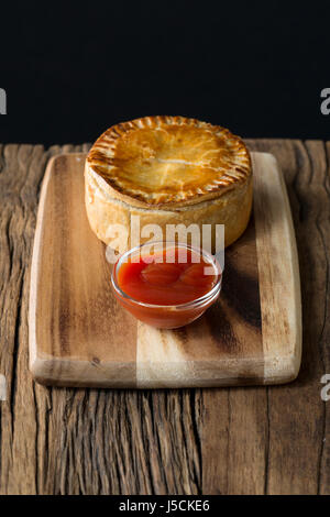 Une tarte de viande britannique traditionnel, assis sur une table en bois rustique. Banque D'Images