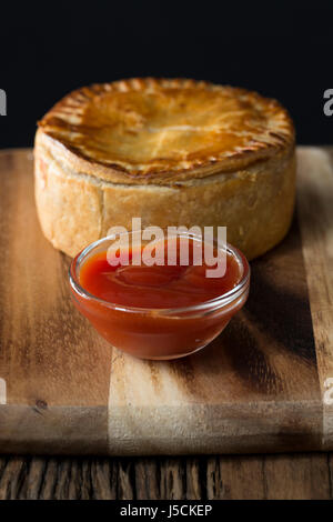 Une tarte de viande britannique traditionnel, assis sur une table en bois rustique. Banque D'Images