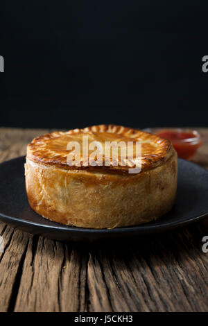 Une tarte de viande britannique traditionnel, assis sur une table en bois rustique. Banque D'Images