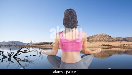 Digital composite de double exposition de woman meditating at lakeshore Banque D'Images