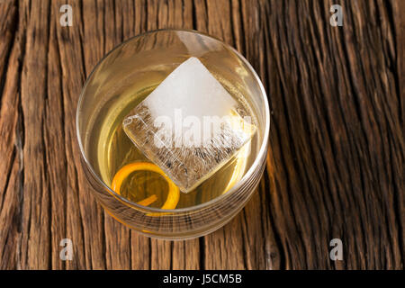 Verre de Scotch whisky sur un vieux fond de bois rustique. Style moderne avec un grand cube de glace et d'écorce d'orange pour la décoration. Banque D'Images