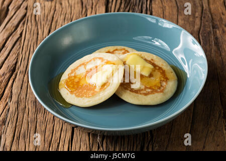 Trois des pancakes dans un bol bleu, assis sur une table en bois rustique. Banque D'Images