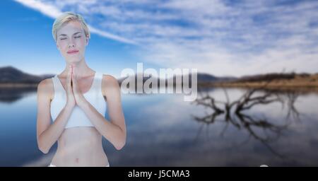 Digital composite de double exposition d'une femme avec les mains jointes contre yoga lake Banque D'Images