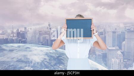 Digital composite of Businesswoman holding slate en face de face contre globe and city Banque D'Images