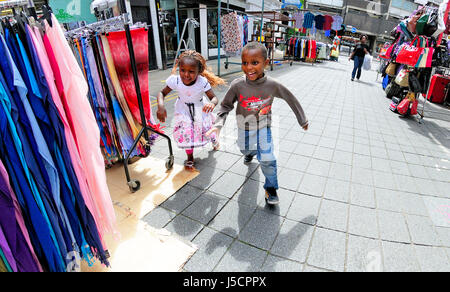 London, UK, Enland. Deux enfants jouant à Wentworth Street Market / Jupon Lane. Banque D'Images