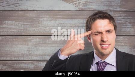 Digital composite of Portrait of businessman visant le front avec le doigt contre la paroi en bois Banque D'Images