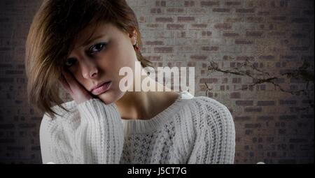 Femme de tête et visage triste dans la main contre le mur de brique marron Banque D'Images