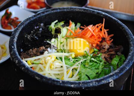 Bibimbap est un favori traditionnel coréen composé de riz vapeur, garni de viande, de matières ou d'œuf frit et des légumes et habituellement servi dans une pierre chaude Banque D'Images